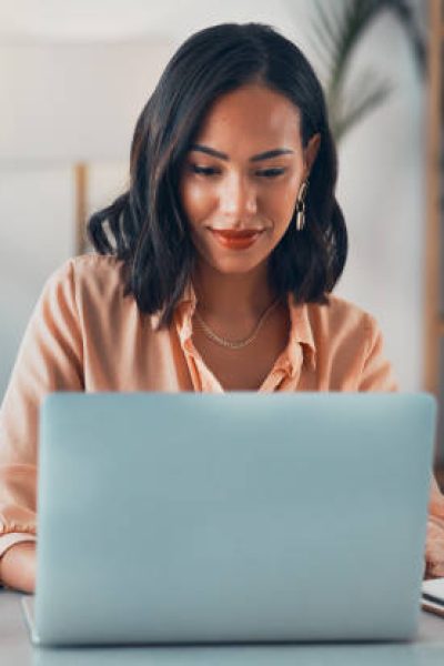 Woman working on laptop online, checking emails and planning on the internet while sitting in an office alone at work. Business woman, corporate professional or manager searching the internet